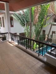 Spacious balcony overlooking a pool with lush greenery