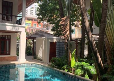 Tropical style outdoor pool surrounded by lush greenery and adjacent to residential buildings