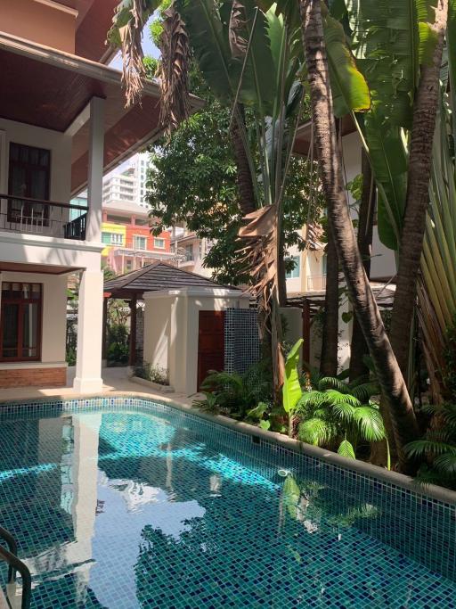 Tropical style outdoor pool surrounded by lush greenery and adjacent to residential buildings