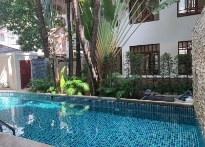 Serene pool area surrounded by lush greenery and part of a residential building