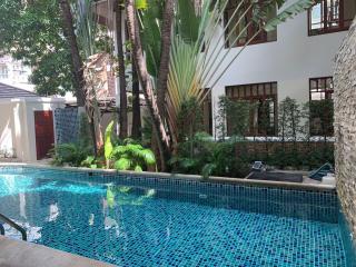 Serene pool area surrounded by lush greenery and part of a residential building