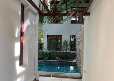 Spacious passage leading to a serene outdoor pool area with lush greenery