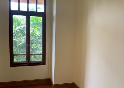 Empty bedroom with wooden floor and a view of greenery through the window