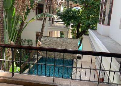 View from the balcony overlooking the swimming pool surrounded by lush greenery