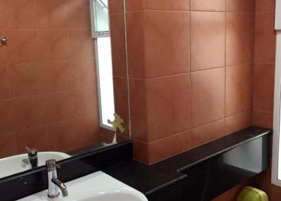 Modern bathroom with terracotta tile walls and a pedestal sink