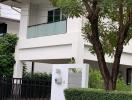 Modern two-story house with a large tree and gated entrance