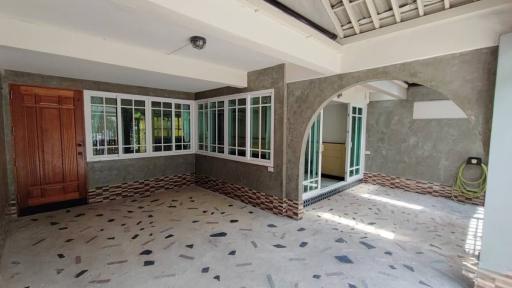 Spacious living room with tiled flooring, arched doorway, and large windows