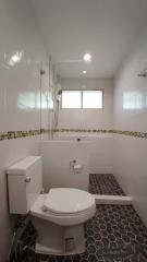 Modern bathroom with tiled walls and floor, shower area, and natural light from a window