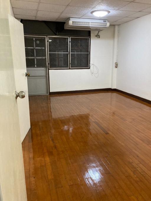 Spacious living room with glossy wooden flooring and air conditioning unit