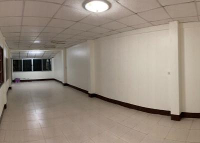 Spacious empty corridor inside a building with white walls and tiled floor