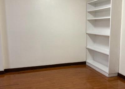 Empty bedroom with hardwood floors and a white bookshelf