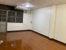 Spacious empty room with wooden flooring and air conditioning