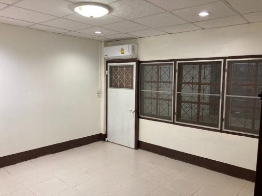 Spacious interior room with tiled flooring, white walls, and an air conditioning unit