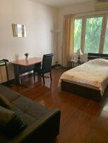 Cozy bedroom with ample natural light, featuring a bed, desk, and seating area