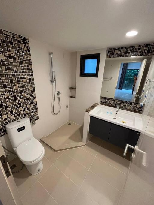 Modern bathroom with walk-in shower, mosaic tiles, and white fixtures