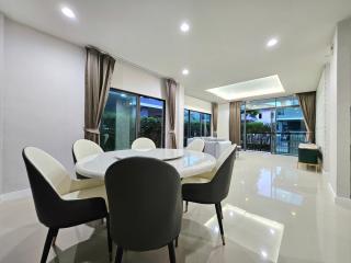 Modern dining room with large white table, sleek chairs, and a view of the patio