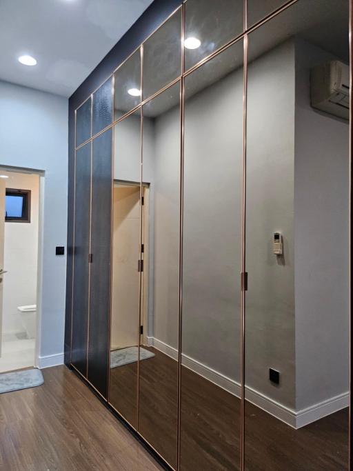 Modern hallway with mirrored closet doors and hardwood floors