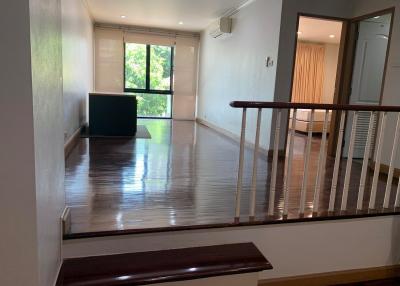 Spacious living room with wooden flooring, large windows, and balcony access