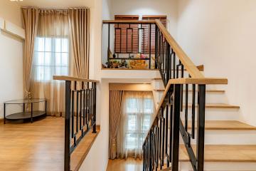 Modern staircase with wooden steps and metal railings in a well-lit home interior
