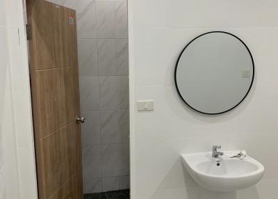 Modern bathroom with white tiling, circular mirror, and a pedestal sink