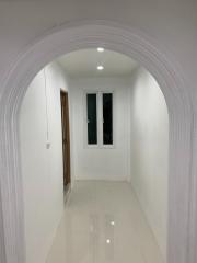 Brightly Lit Hallway Leading to Rooms with White Walls