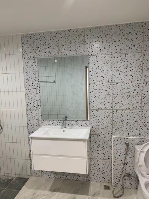 Modern bathroom with terrazzo tiling, floating vanity, and glass shower door