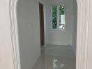 Bright and spacious white corridor with arched doorway and glossy tiled floor