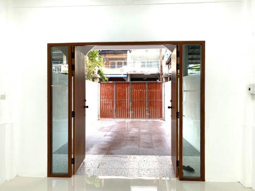 View from open front doors of a residence showcasing a clean, tiled entrance area leading to a secure wooden gate