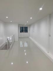 Modern interior view of a well-lit, spacious building with white walls and glossy tiled flooring