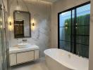 Modern bathroom with marble walls, freestanding tub, and glass shower