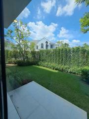 View from a patio looking out to a manicured backyard and neighboring house