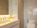 Modern bathroom with neutral tones featuring a vanity sink, toilet, and glass shower enclosure