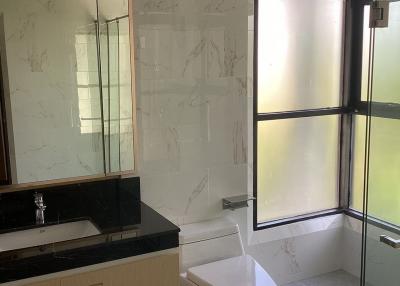 Modern bathroom with glass shower enclosure, toilet, and vanity area