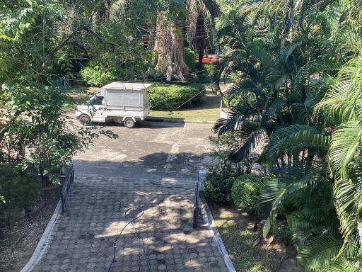 View of the exterior from a window showing a green area, a truck and paved path