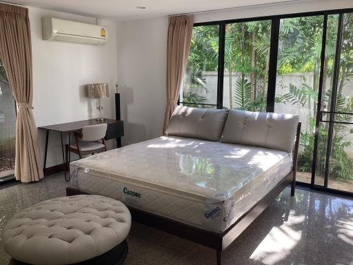 Spacious bedroom with natural lighting and a view of greenery