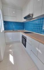 Modern kitchen with blue tile backsplash and wooden countertops