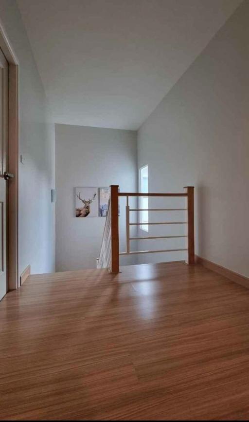 Spacious hallway with hardwood flooring and modern railing