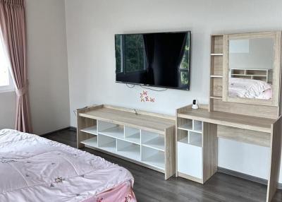 Clean and modern bedroom with mounted television and study area