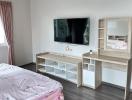 Clean and modern bedroom with mounted television and study area