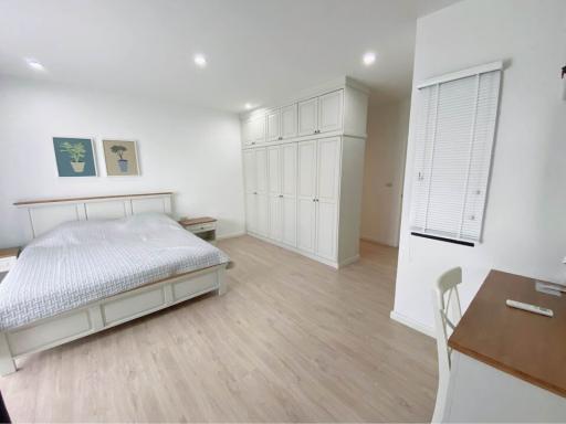 Spacious bedroom with large bed, wooden flooring, and ample storage