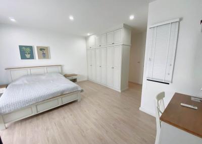 Spacious bedroom with large bed, wooden flooring, and ample storage