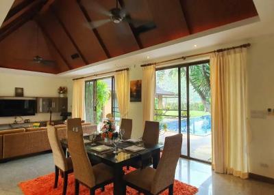 Spacious living room with high ceiling, dining area, and garden view