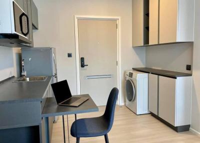 Modern kitchen with stainless steel appliances, laptop on the counter, and in-unit laundry