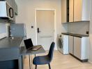 Modern kitchen with stainless steel appliances, laptop on the counter, and in-unit laundry
