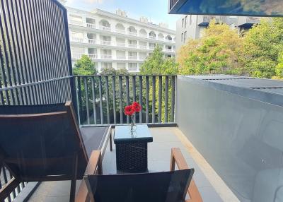 Small balcony with two chairs and a table overlooking urban environment