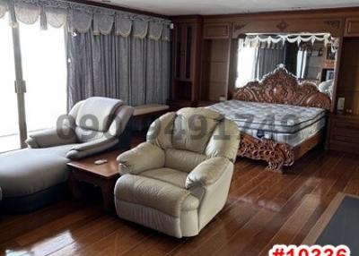 Spacious bedroom with wood-paneled walls and hardwood flooring