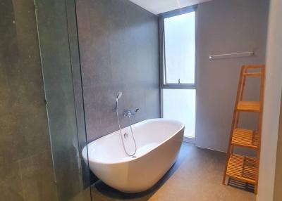 Modern bathroom with a freestanding tub, walk-in shower, and a large window