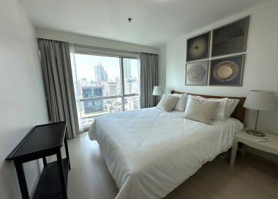 Modern bedroom with a large window overlooking the city