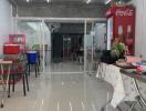 Spacious interior of a commercial building with dining setup and Coca-Cola fridge