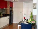 Modern kitchen with dining area featuring elegant flower decoration and red accents